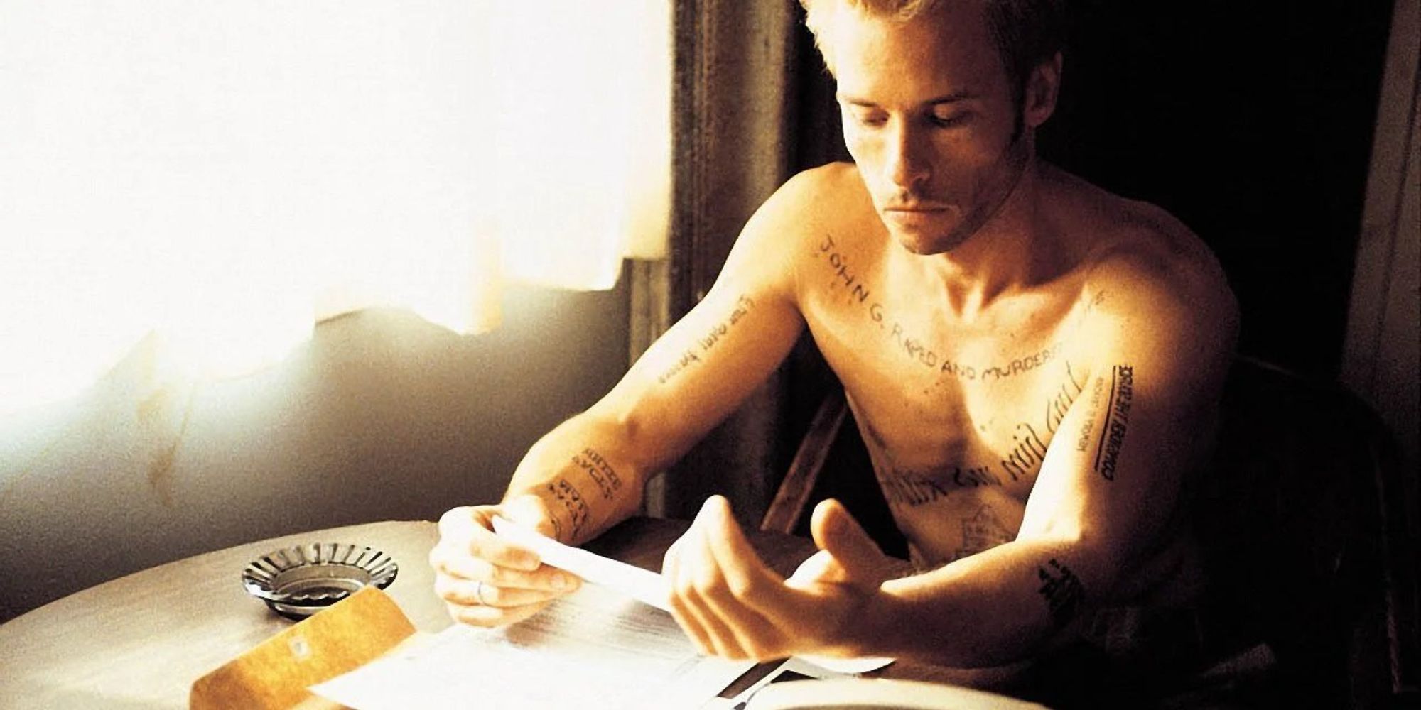 Leonard Shelby, sitting at a table reading documents in 'Memento'