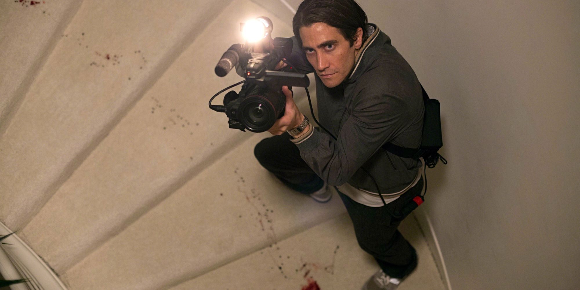 Lou aims his camera up while climing a set of stairs in the film Nightcrawler.