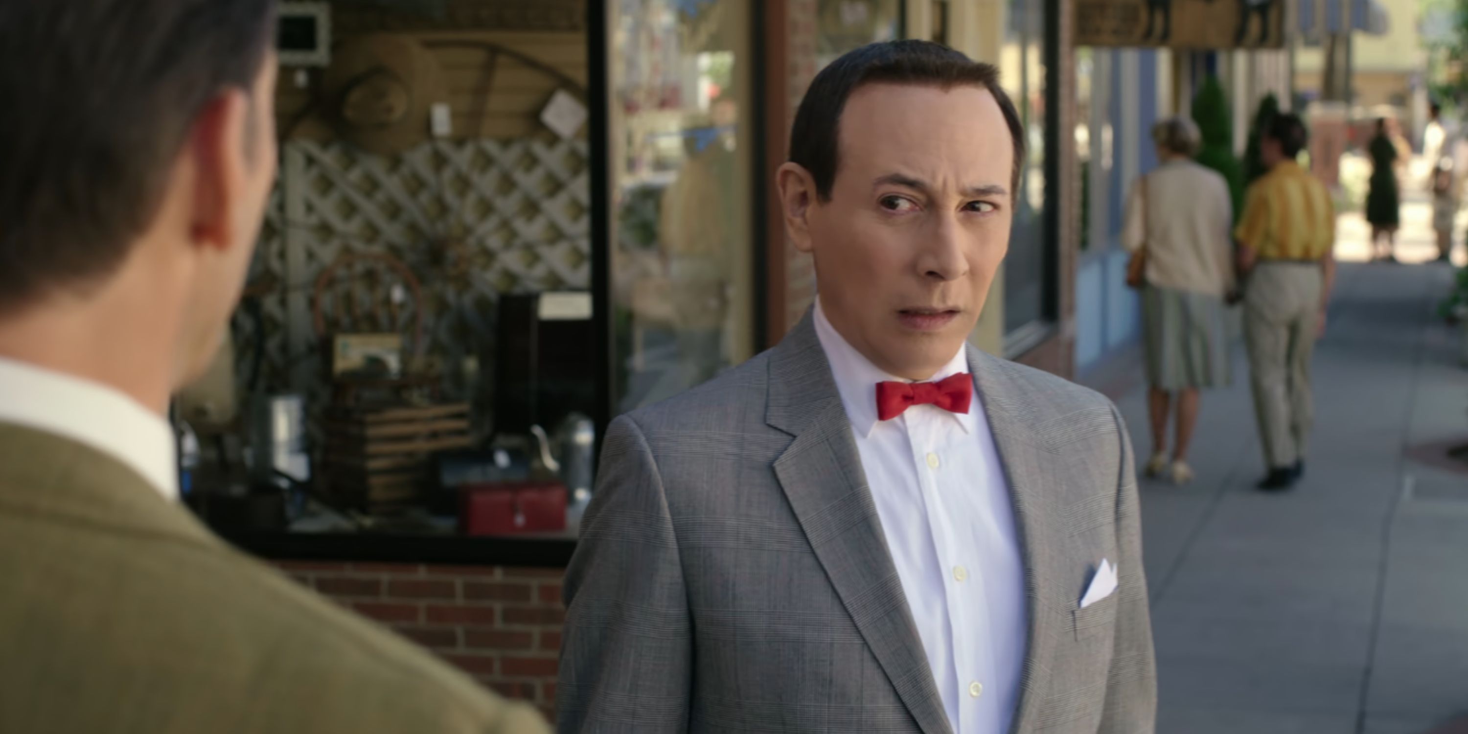 Paul Reubens as Pee-wee Herman, a man in a suit and bowtie in 'Pee-wee's Big Holiday'