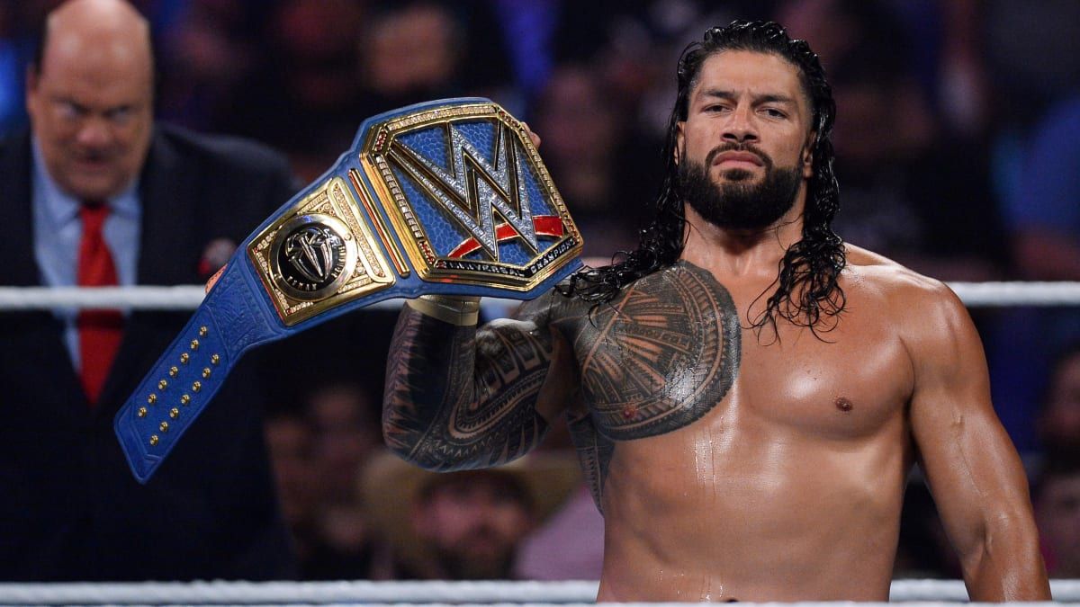 WWE star Roman Reigns holding up his championship belt in the ring.