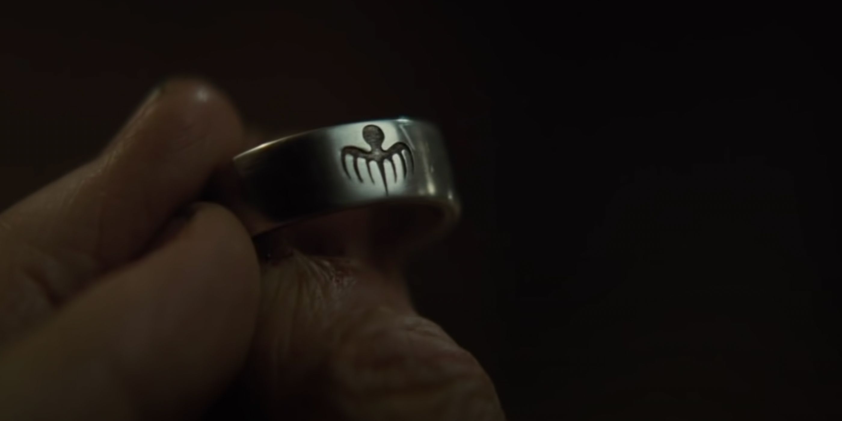 Mr. White holds a Spectre ring while talking with James Bond (Daniel Craig).
