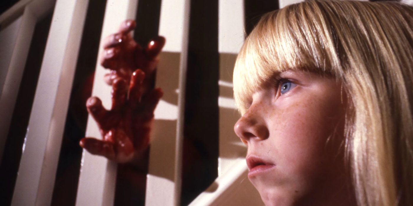 A young girl looking ahead while bloody hands come out of the bannister beside her in The Brood.