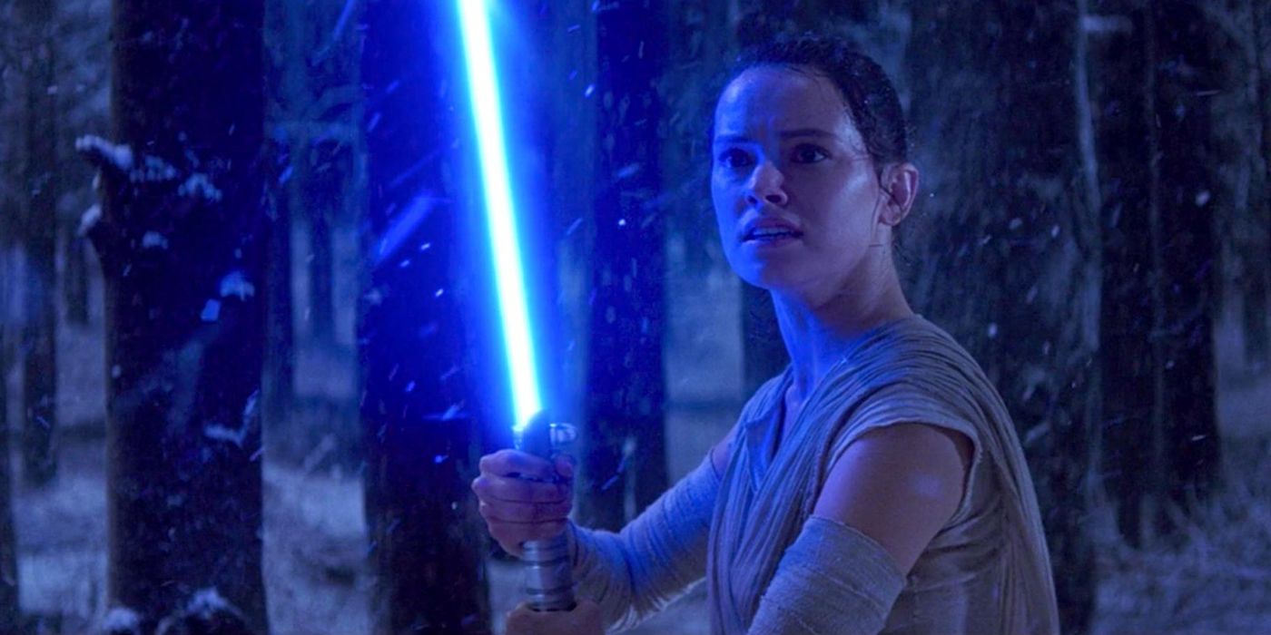 Rey wielding a lightsaber in a dark snowy forest in The Force Awakens