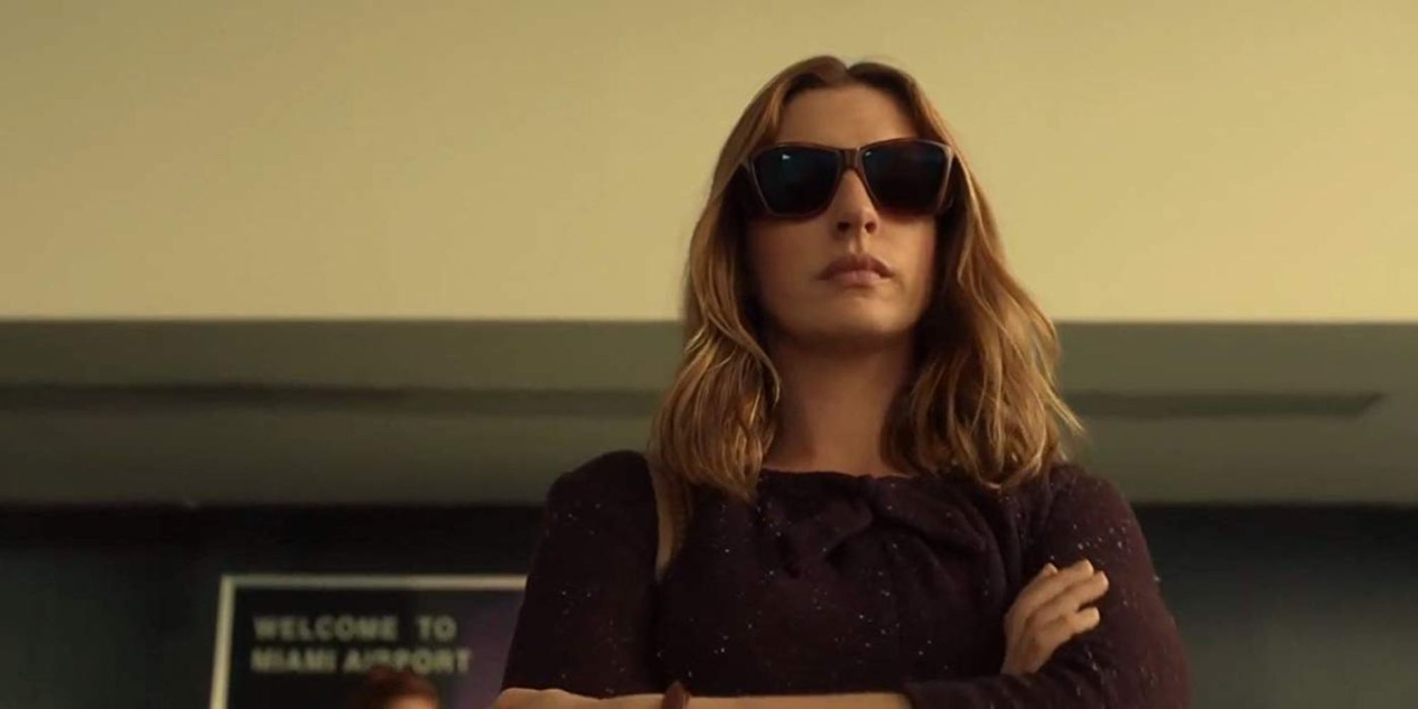 Anne Hathaway, wearing shades and crossing her arms, in The Last Thing He Wanted