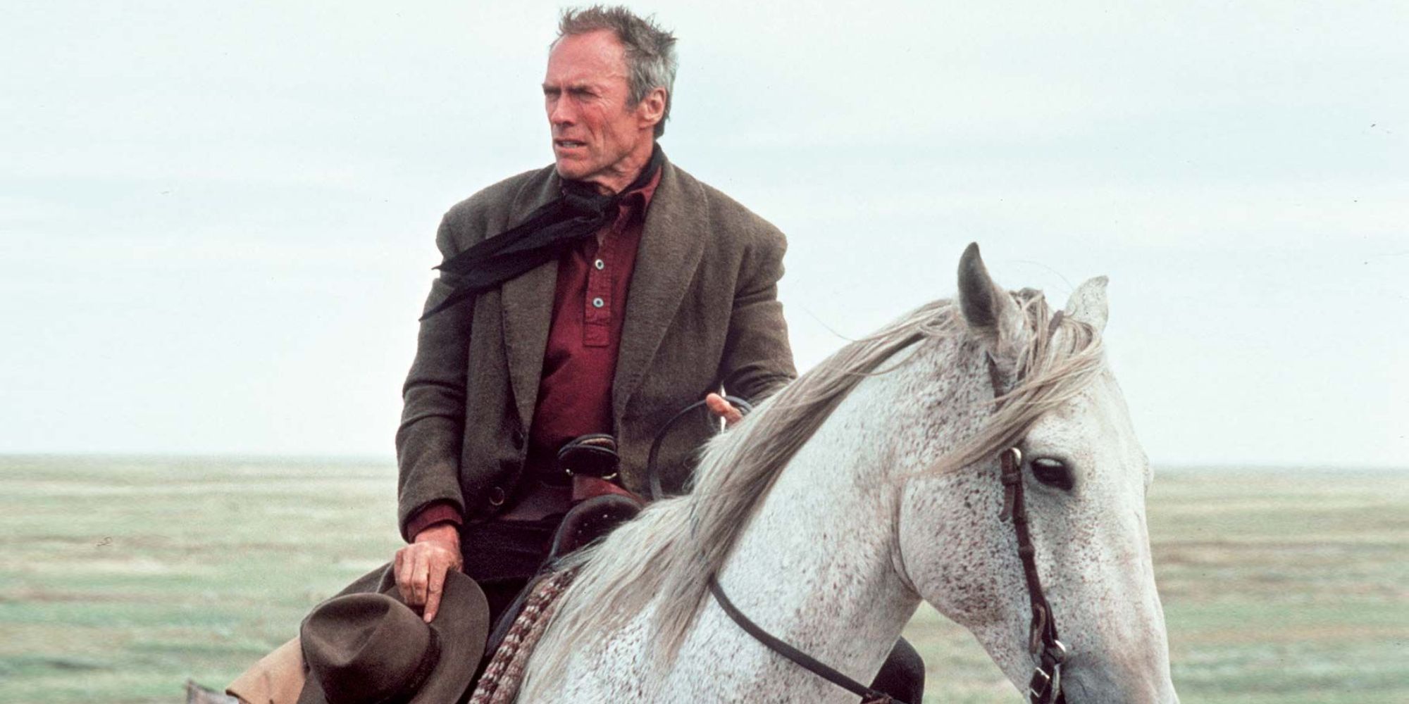 Clint Eastwood como Bill Munny andando a cavalo em Unforgiven, 1992