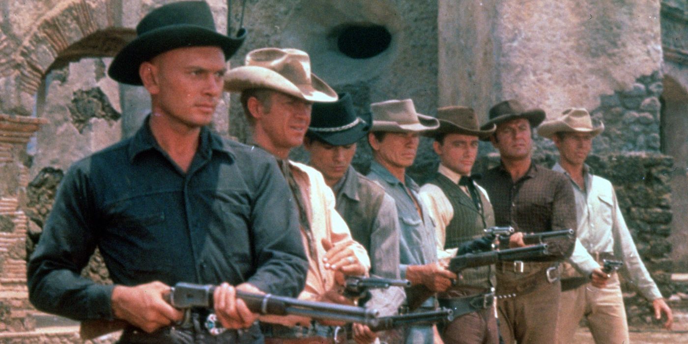 Os Sete Magníficos em fila apontando seus rifles na mesma direção no filme Os Sete Magníficos.