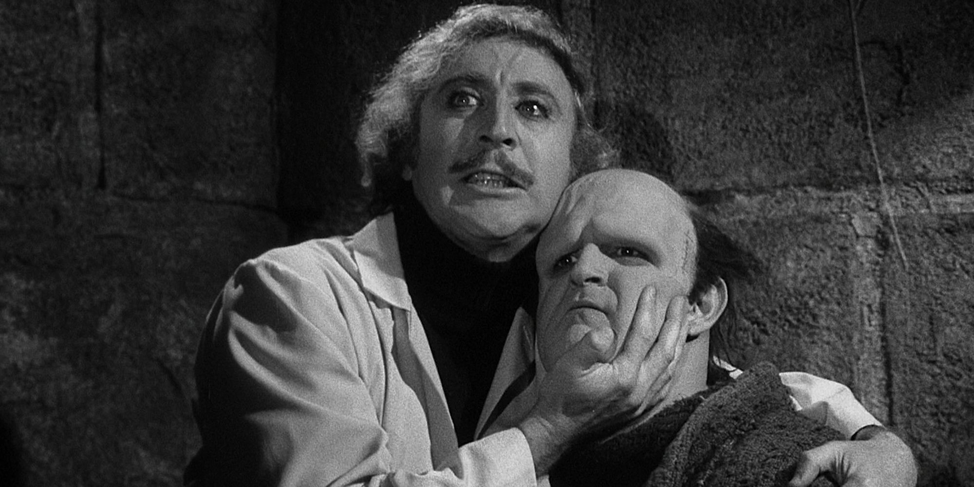 Dr. Frederick Frankenstein (Gene Wilder) holds the face of the Monster (Peter Boyle) as he glares with manic intensity.