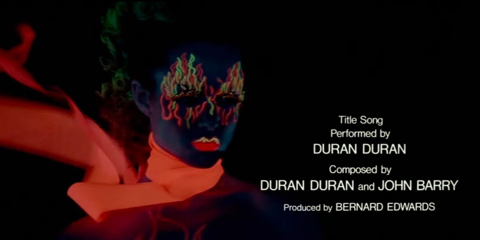 A woman's bright orange scarf and make-up glow in the blacklight during the opening credits of 'A View to a Kill'.