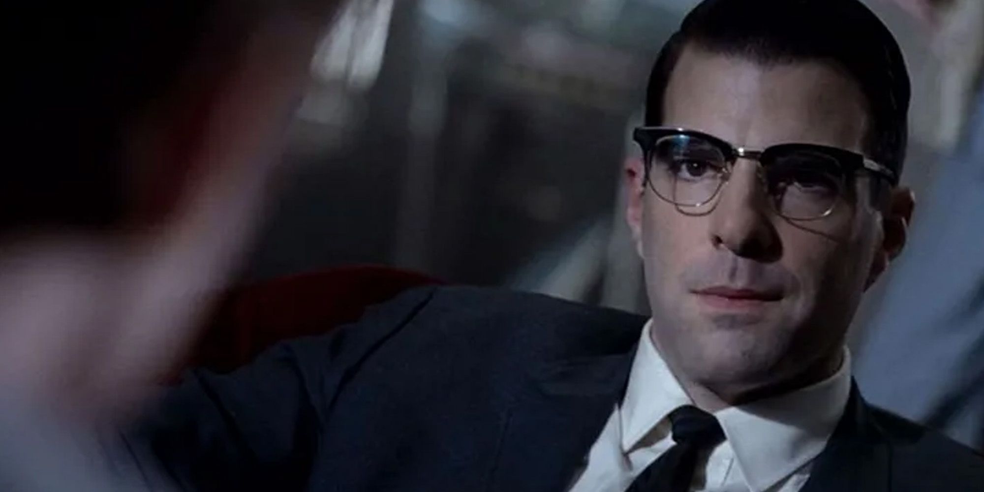 Dr. Oliver Thredson, played by actor Zachary Quinto, wearing a suit with a smirk on his face in 'AHS: Asylum'