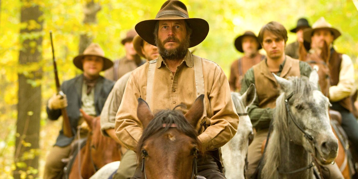 Bill Paxton a caballo conduce a un grupo de hombres a través de los bosques de Hatfields y McCoys.