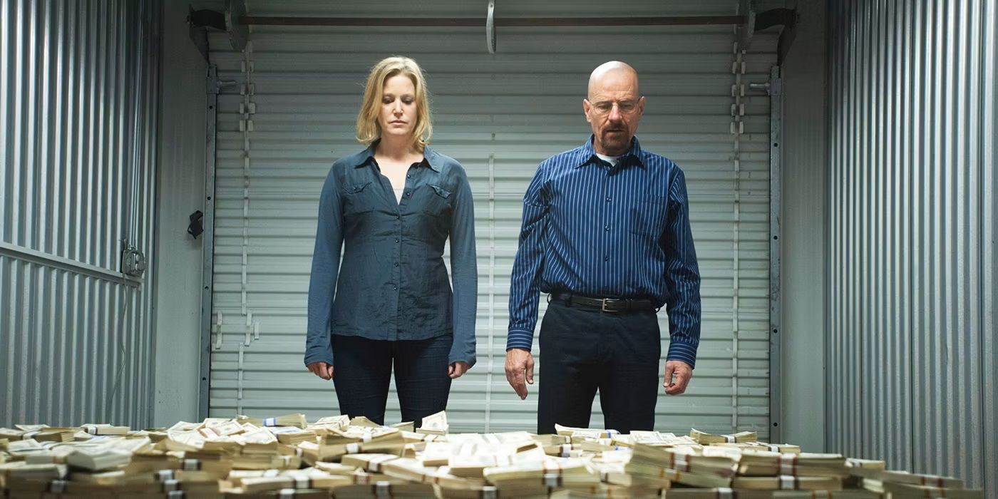 Bryan Cranston as Walter White and Anna Gunn Skylar White standing in front of a pile of money in Breaking Bad