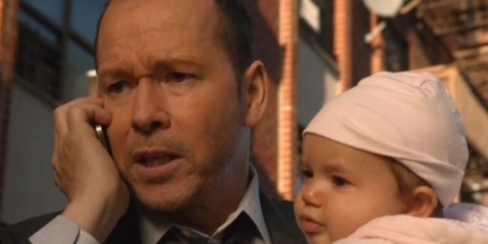 NYPD Detective Danny Reagan holding a baby in Blue Bloods. 