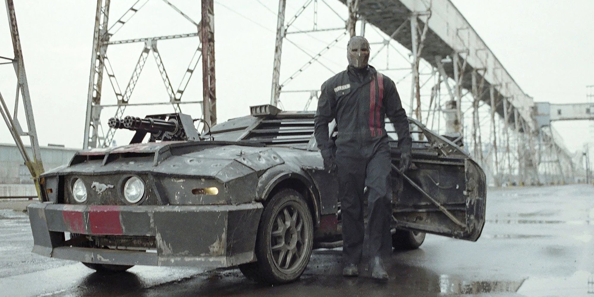 A masked man standing in front of a car