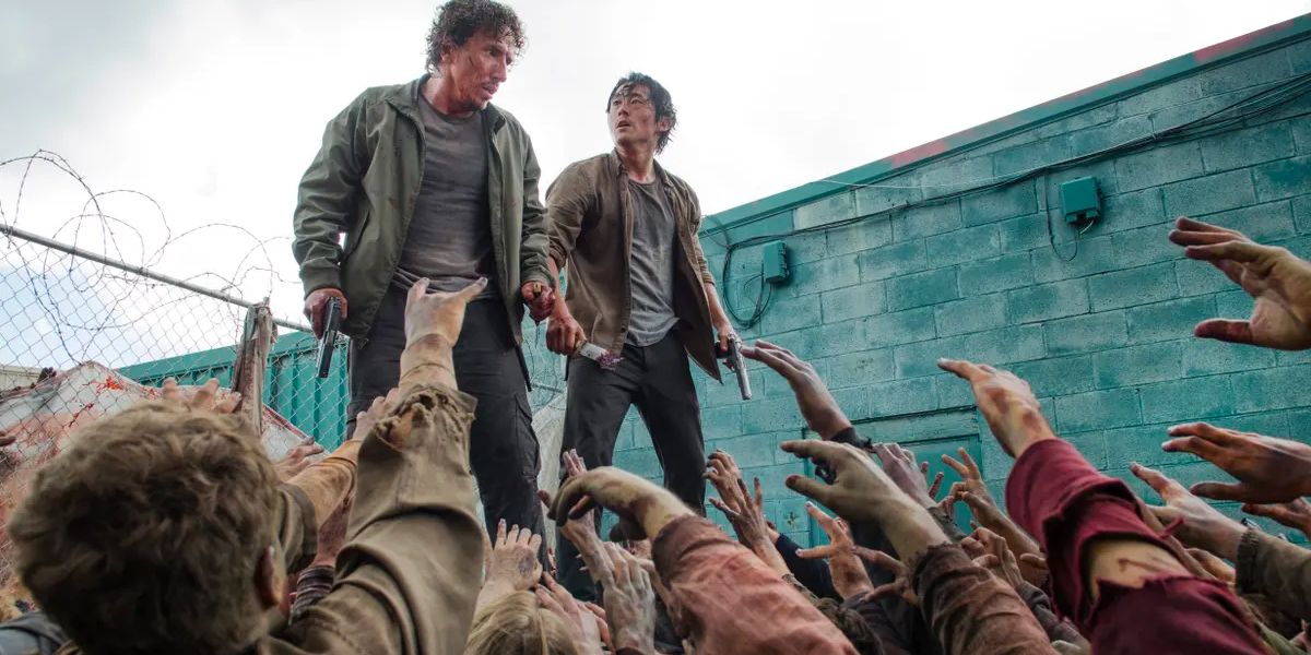 Glenn and Nicholas stand atop a dumpster as they are attacked by a swarm of walkers.