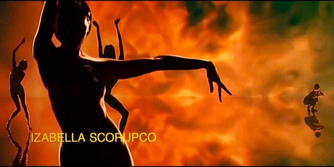 The silhouettes of women dance against an explosive, fiery backdrop. 