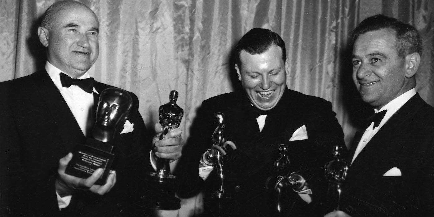 Harold Russell holding his Oscar and laughing alongside Samuel Goldwyn and director William Wyler