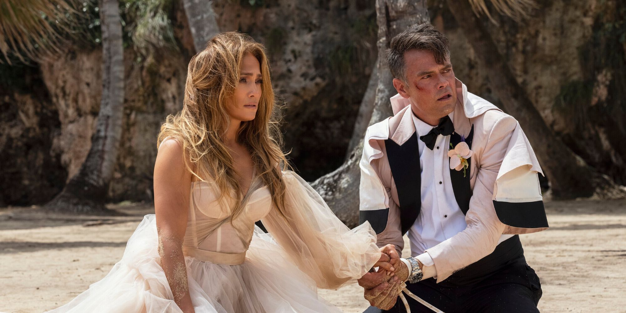 Jennifer Lopez and Josh Duhamel sitting on the beach sand in Shotgun Wedding