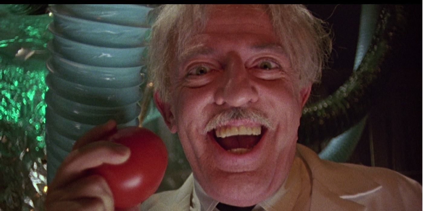 Dr. Gangreen, holding an outlawed tomato and smiling in 'Return of the Killer Tomatoes'