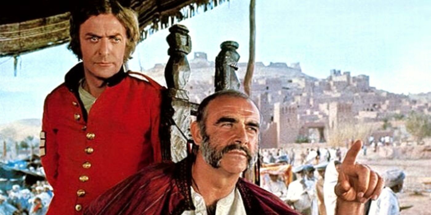 Michael Caine standing behind Sean Connery sitting in a chair in The Man Who Would Be King