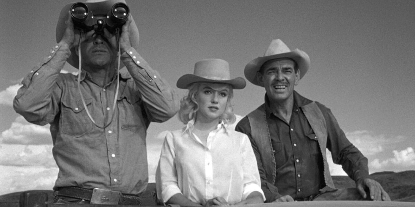 Montgomery Clift, Marilyn Monroe and Clark Gable standing shoulder to shoulder in the back of a truck bed in The Misfits