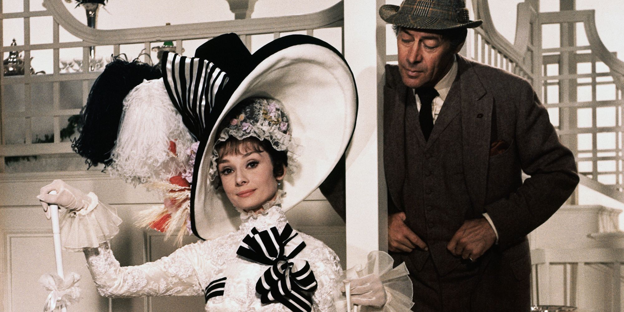 Professor Higging standing behind Eliza, who's sitting on a chair, in My Fair Lady