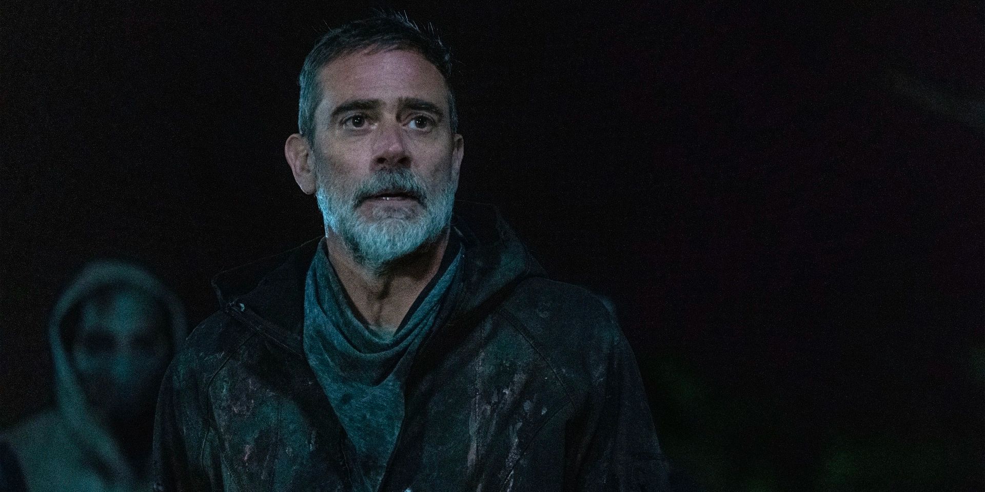 Negan looks disparagingly towards someone while standing in darkness. 