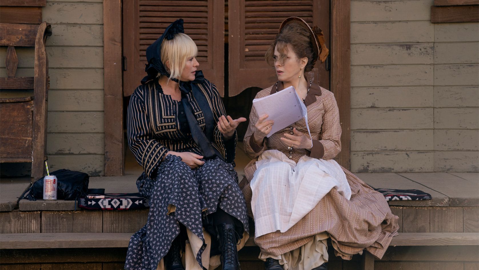 patricia arquette and bernadette peters in pioneertown costumes with script sitting on stairs in high desert