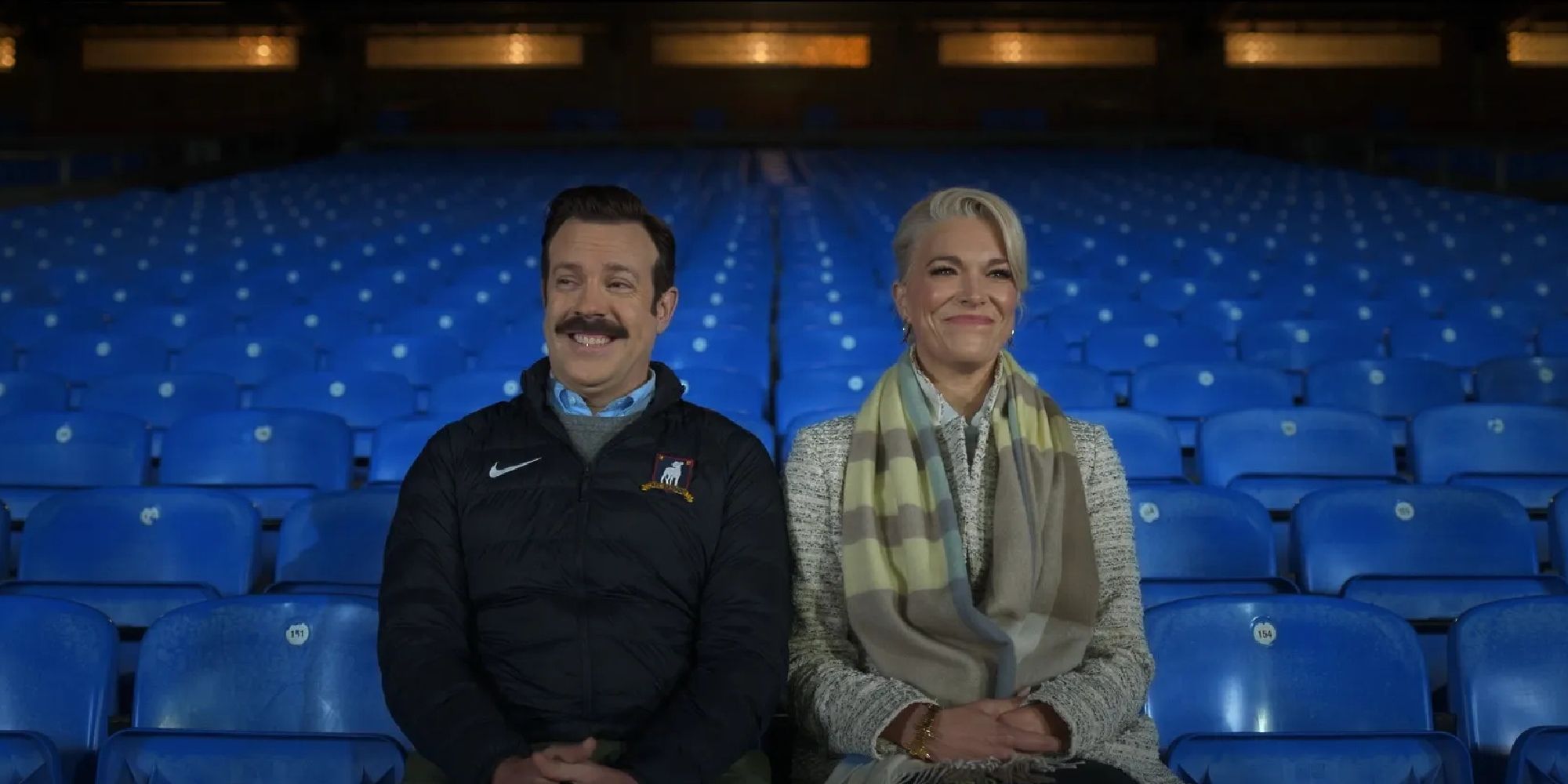 Ted Lasso (Jason Sudeikis) y Rebecca (Hannah Waddingham) se sientan juntos en un auditorio vacío durante el final de la tercera temporada de Ted Lasso, 