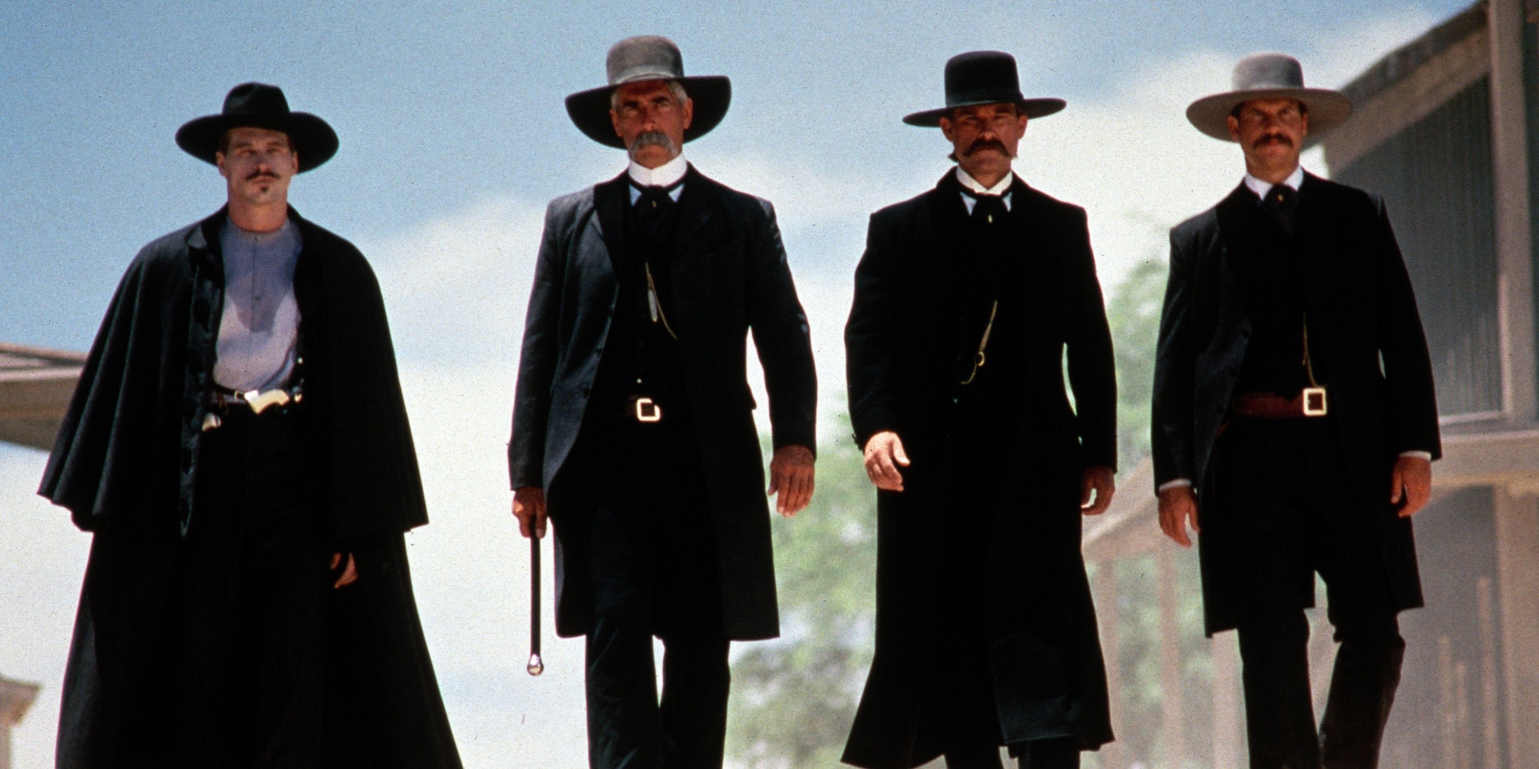 four cowboys dressed in black walking through deserted town