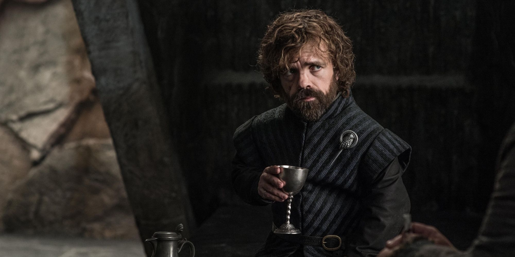 Peter Dinklage as Tyrion Lannister sitting down and drinking from a goblet in Game of Thrones.