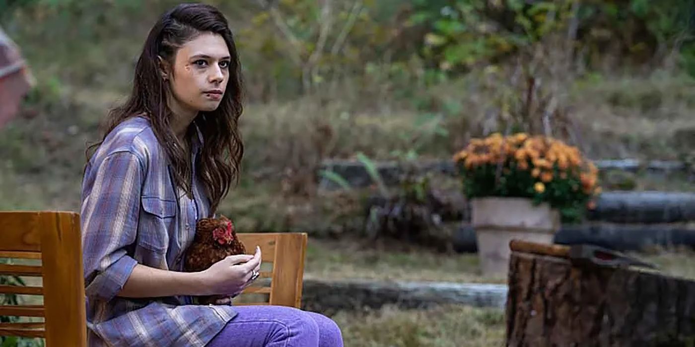 Lisa sitting on a chair holding something, looking unimpressed in a scene from Yellowjackets.