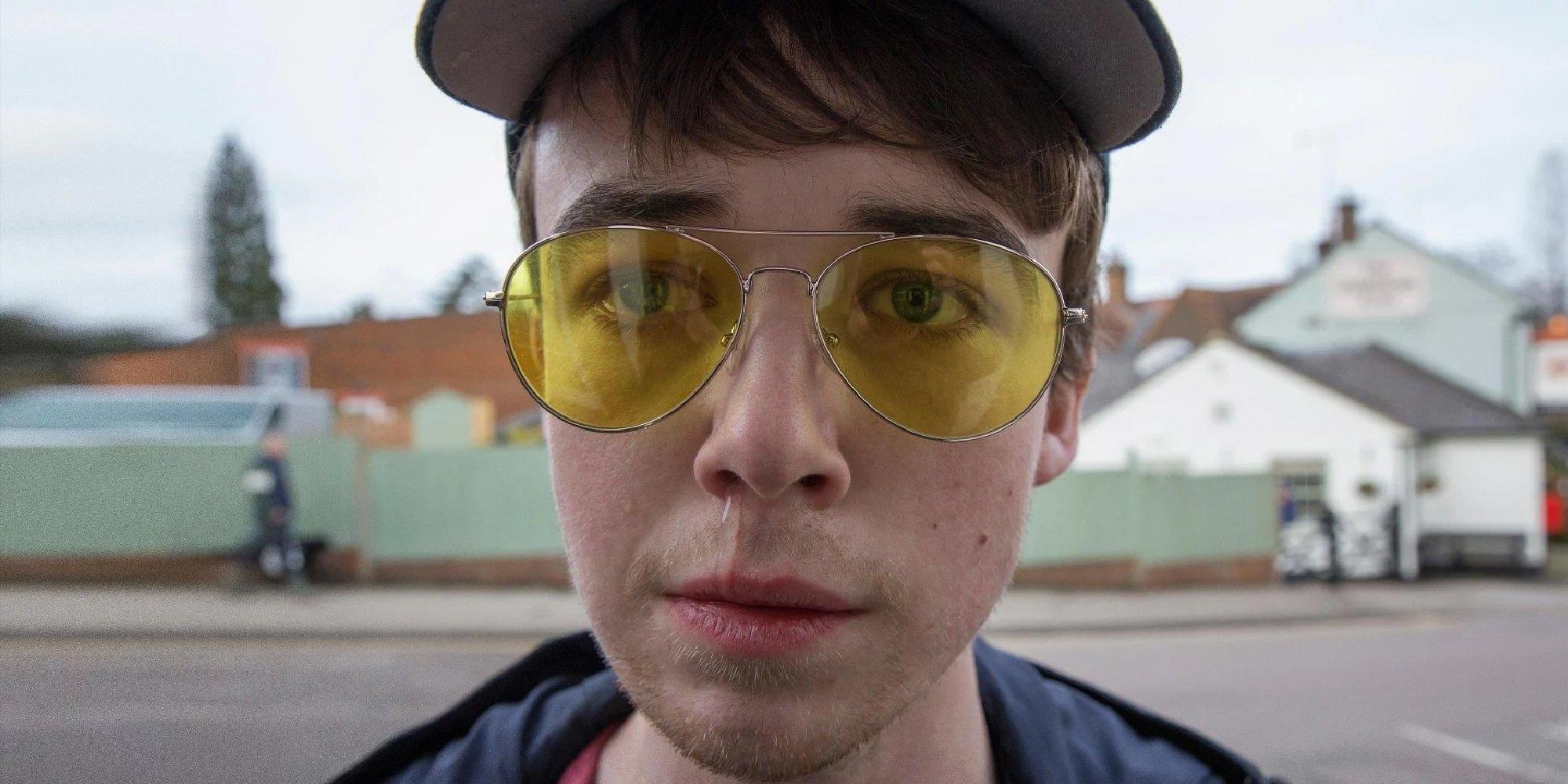 A closeup of Alex Lawther wearing yellow glasses and a hat in Shut Up and Dance in Black Mirror.