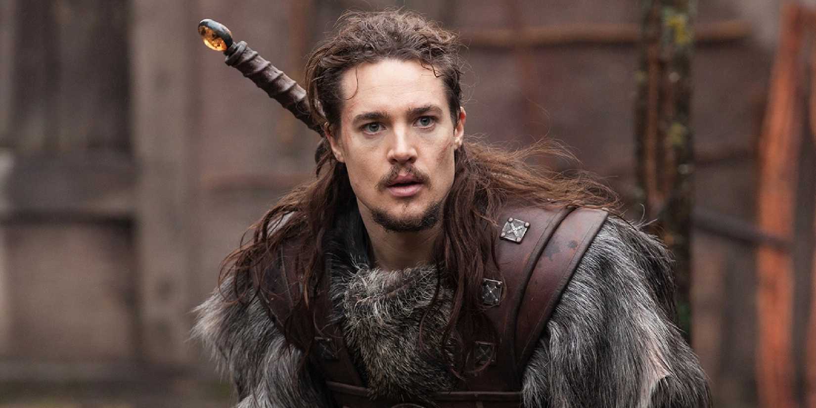 Alexander Dreymon in a fur capelet looking intently off-camera in The Last Kingdom.