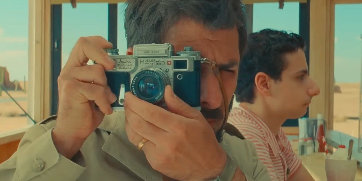 Jason Schwartzman as Augie Steenbeck using a camera to snap a picture in Asteroid City