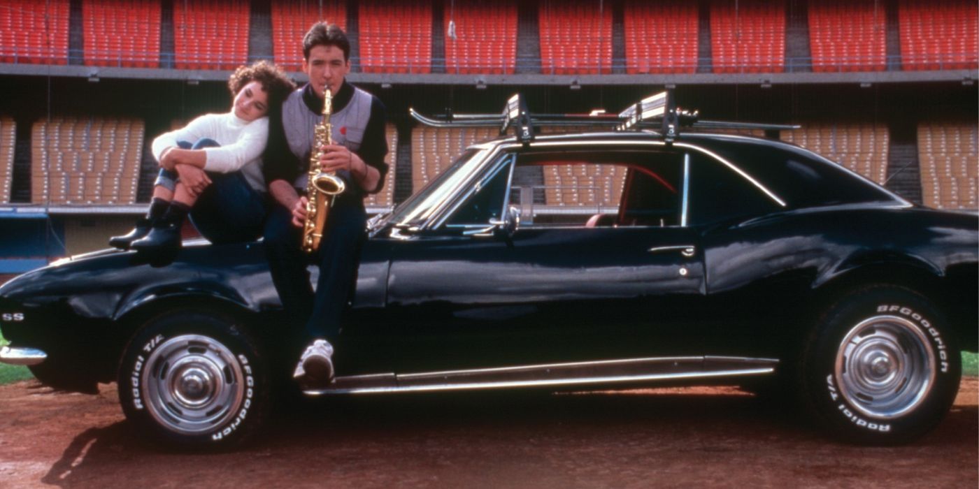 John Cusack with a saxophone and a girl by his side while sitting on the hood of a car in &lsquo;Better Off Dead&rsquo;
