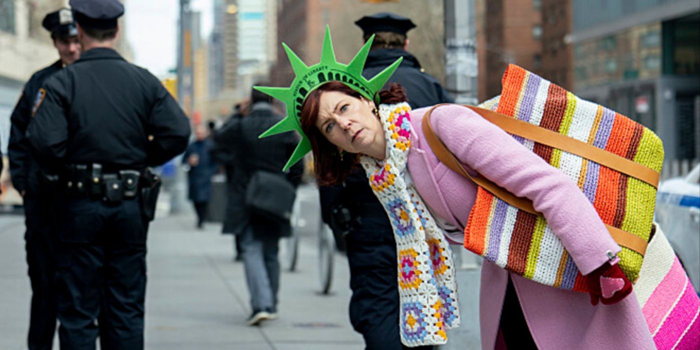 Carrie Preston wearing a lady liberty headband and a pink coat in a scene from Elsbeth
