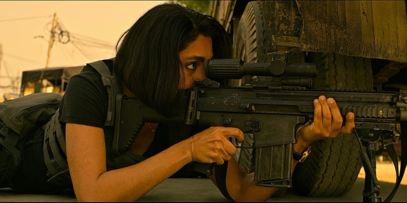 Golshifteh Farahani as Nik, hiding behind the wheel of a car and pointing a rifle in Netflix's Extraction