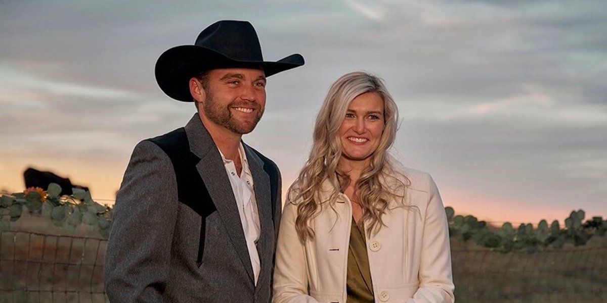 a pair of contestants from Farmer Wants a Wife, the man wears a cowboy hat and a grey suit and the woman is blond with a white coat and they appear to be standing in a field