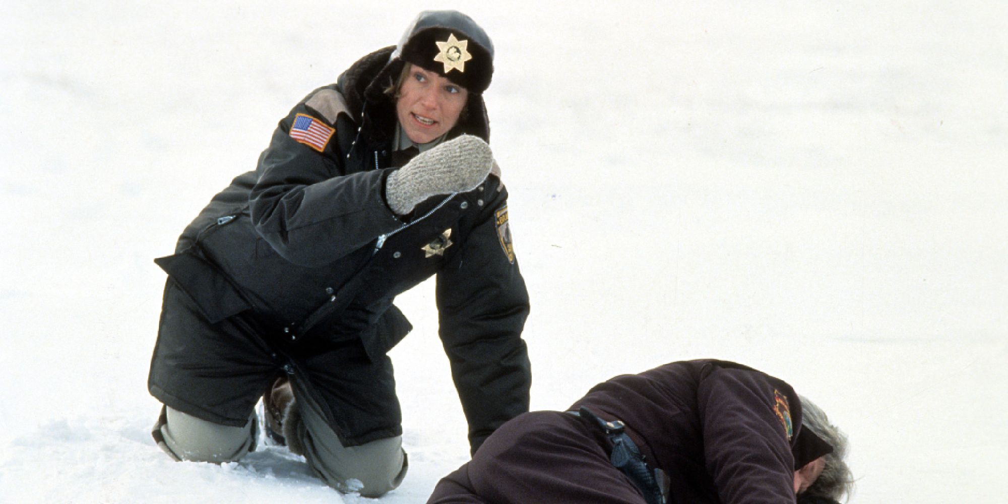 Marge Gunderson, looking scared and kneeling next to a prone body in Fargo