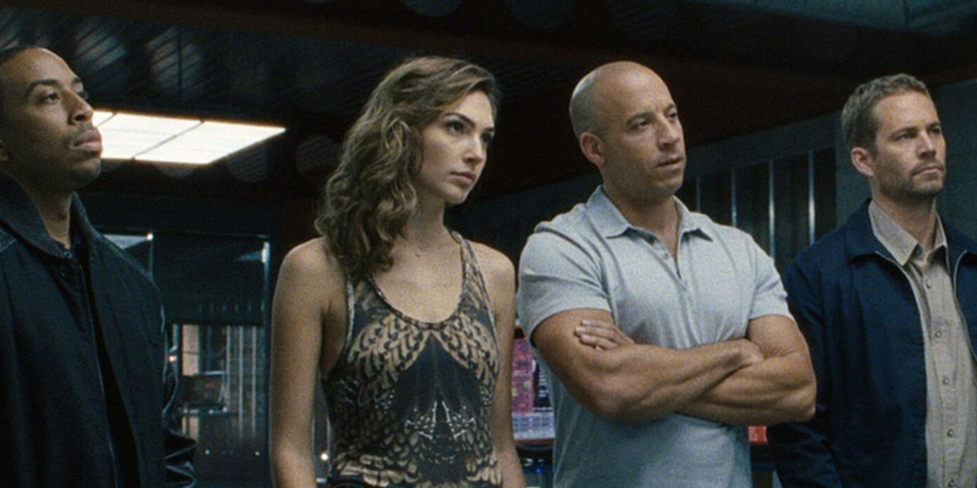 Ludacris, Gal Gadot, Vin Diesel, and Paul Walker as Tej, Giselle, Dom, and Brian standign in line and looking attentive in Fast & Furious 6