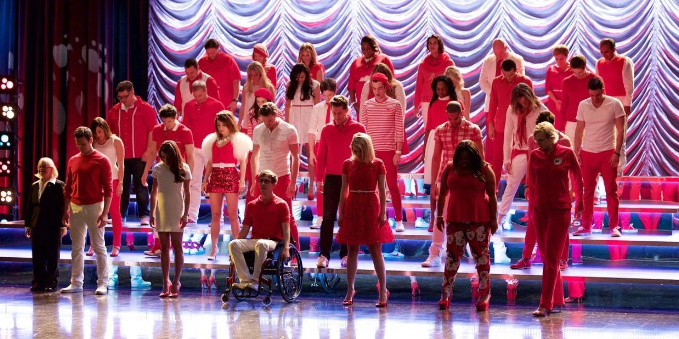 The cast of Glee, New Directions, on stage performing.