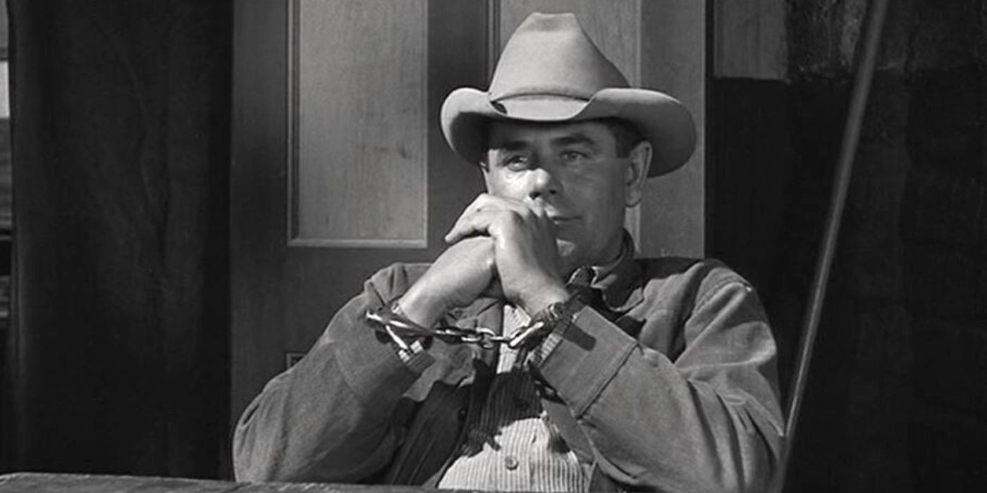 Glenn Ford sitting at a table in handcuffs in 3:10 to Yuma