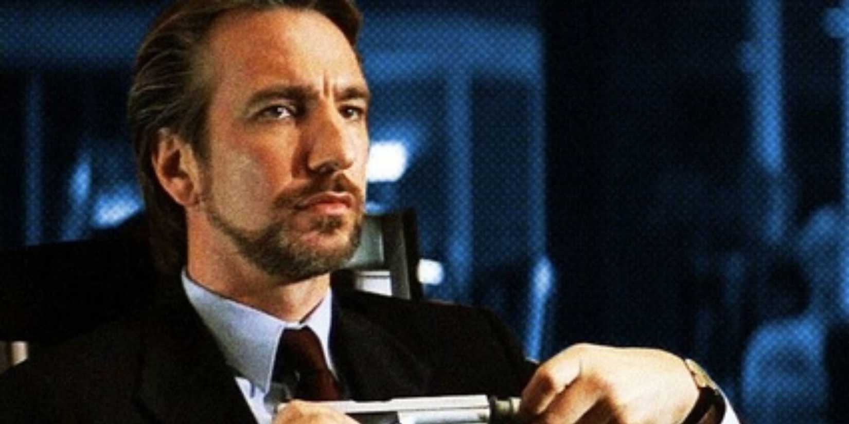 Hans Gruber (Alan Rickman) holding a gun in Die Hard.