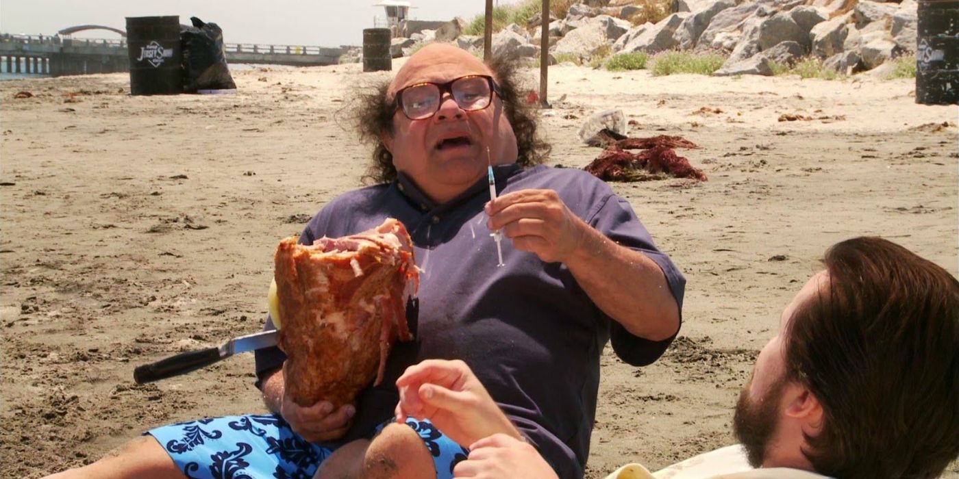 Danny Devito as Frank Reynolds sitting on a beach with a rum ham in It&rsquo;s Always Sunny