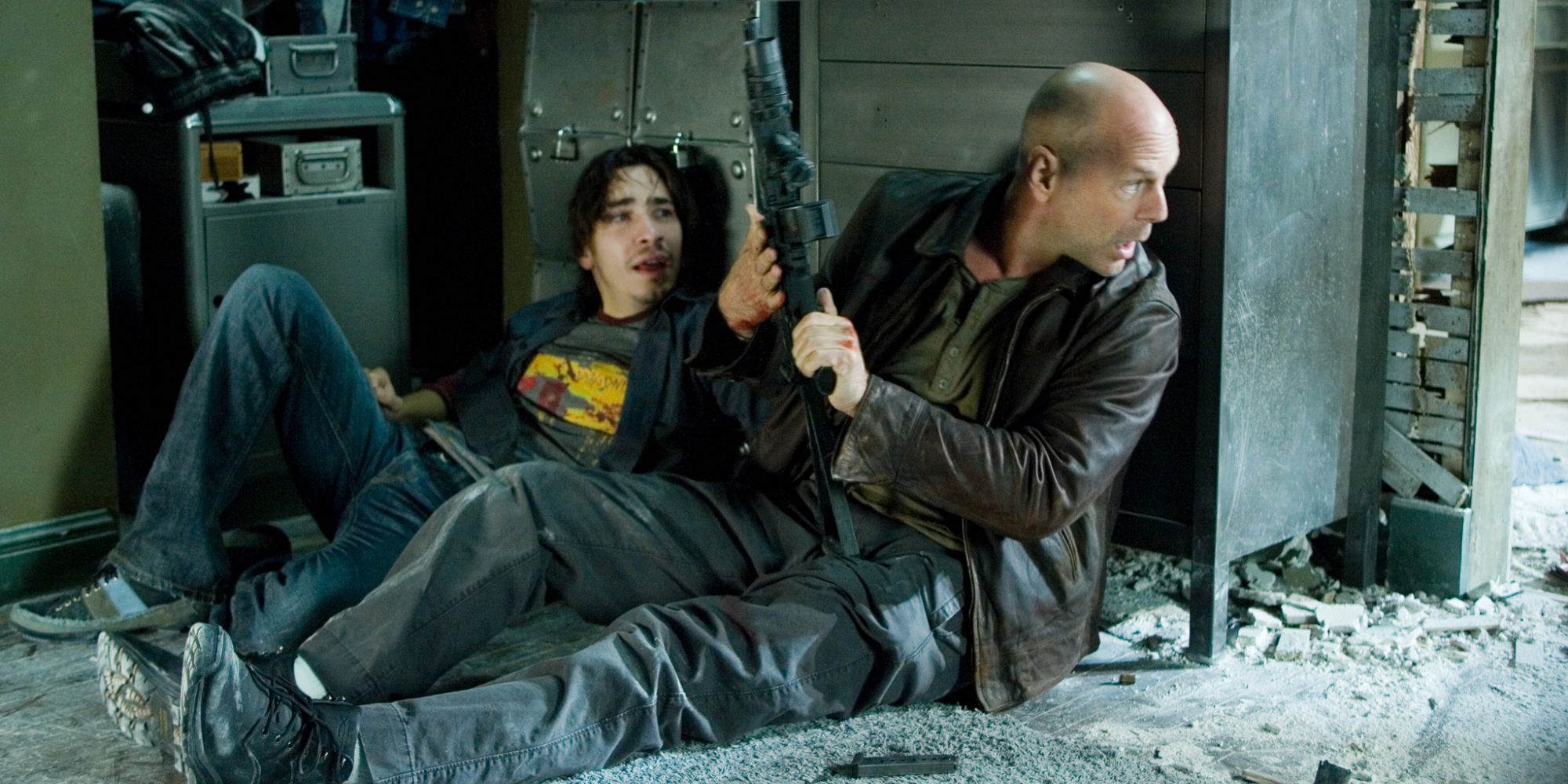 Justin Long and Bruce Willis as Matt Farrell and John Maclaine hiding behind a wall in Live Free or Die Hard (2007)