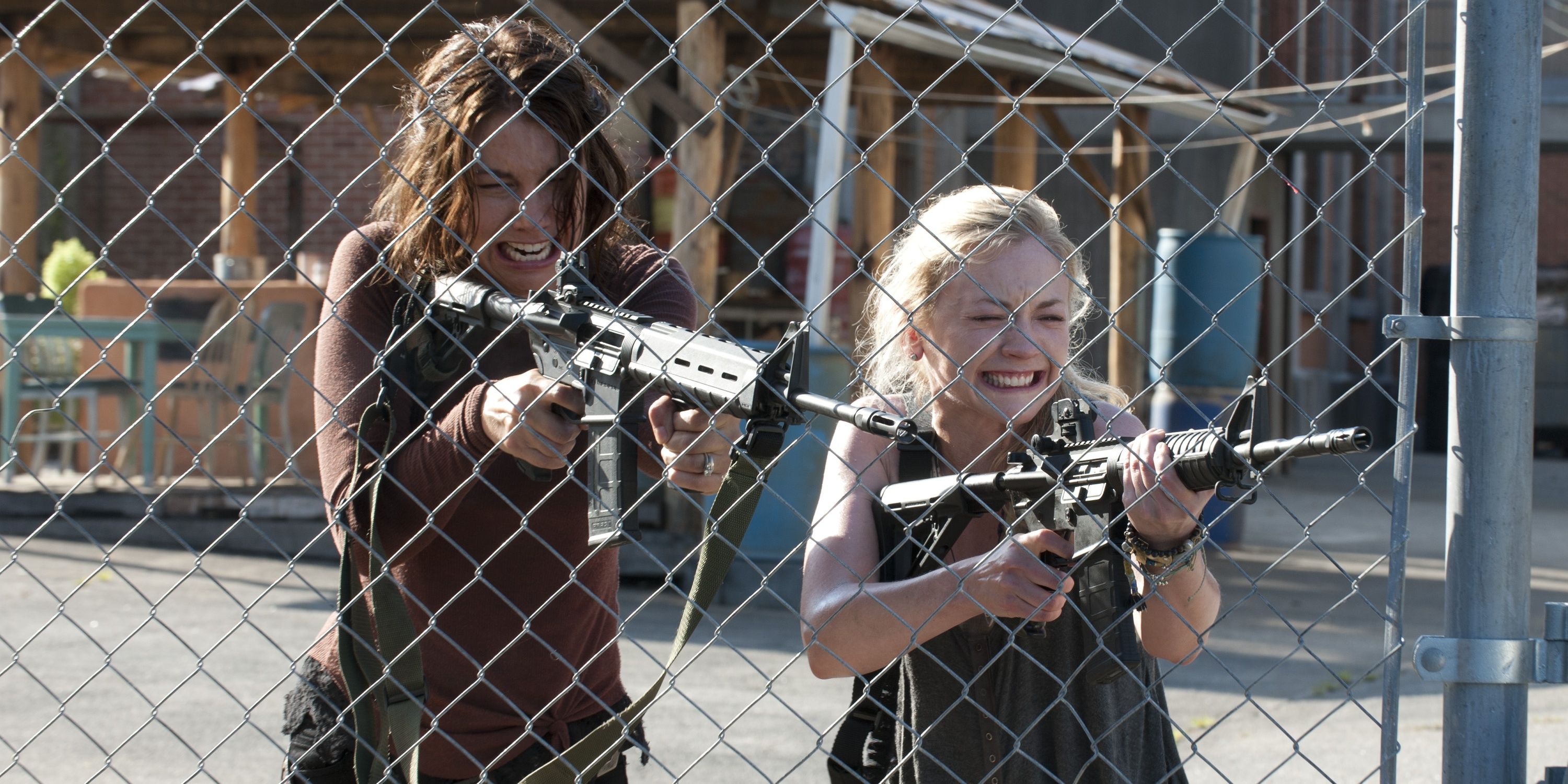 Lauren Cohan as Maggie and Emily Kinney as Beth on The Walking Dead crying and aiming guns through a fence