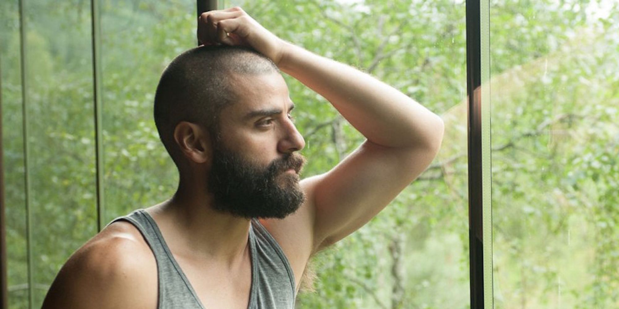 Oscar Isaac leaning against a window in 'Ex Machina' (2014)