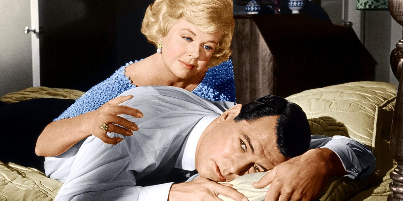 Doris Day leans over Rock Hudson, lying face down on the bed, in 
