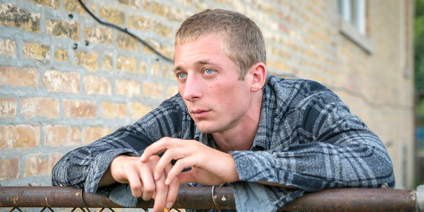 Jeremy Allen White as Lip, leaning on a fence and wearing a plaid shirt in Shameless