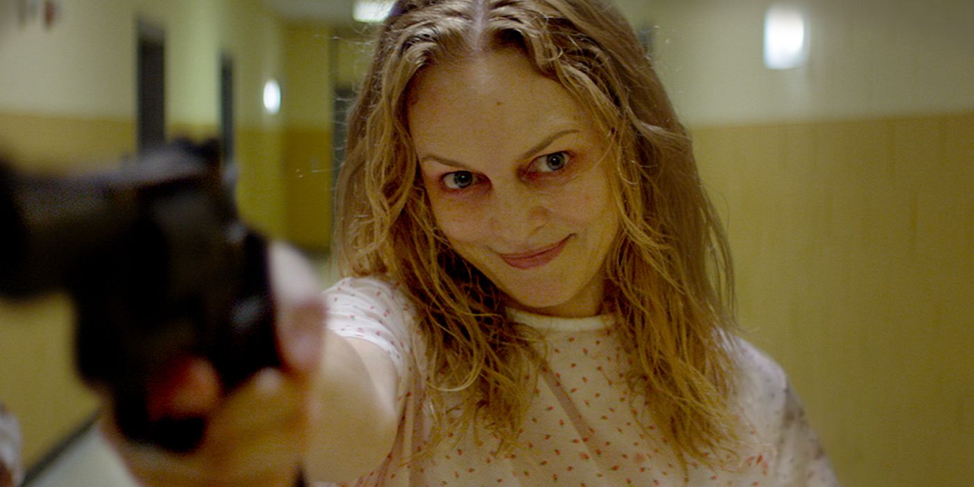 Heather Graham as Dr. Elizabeth Derby holding a gun and smiling in Suitable Flesh